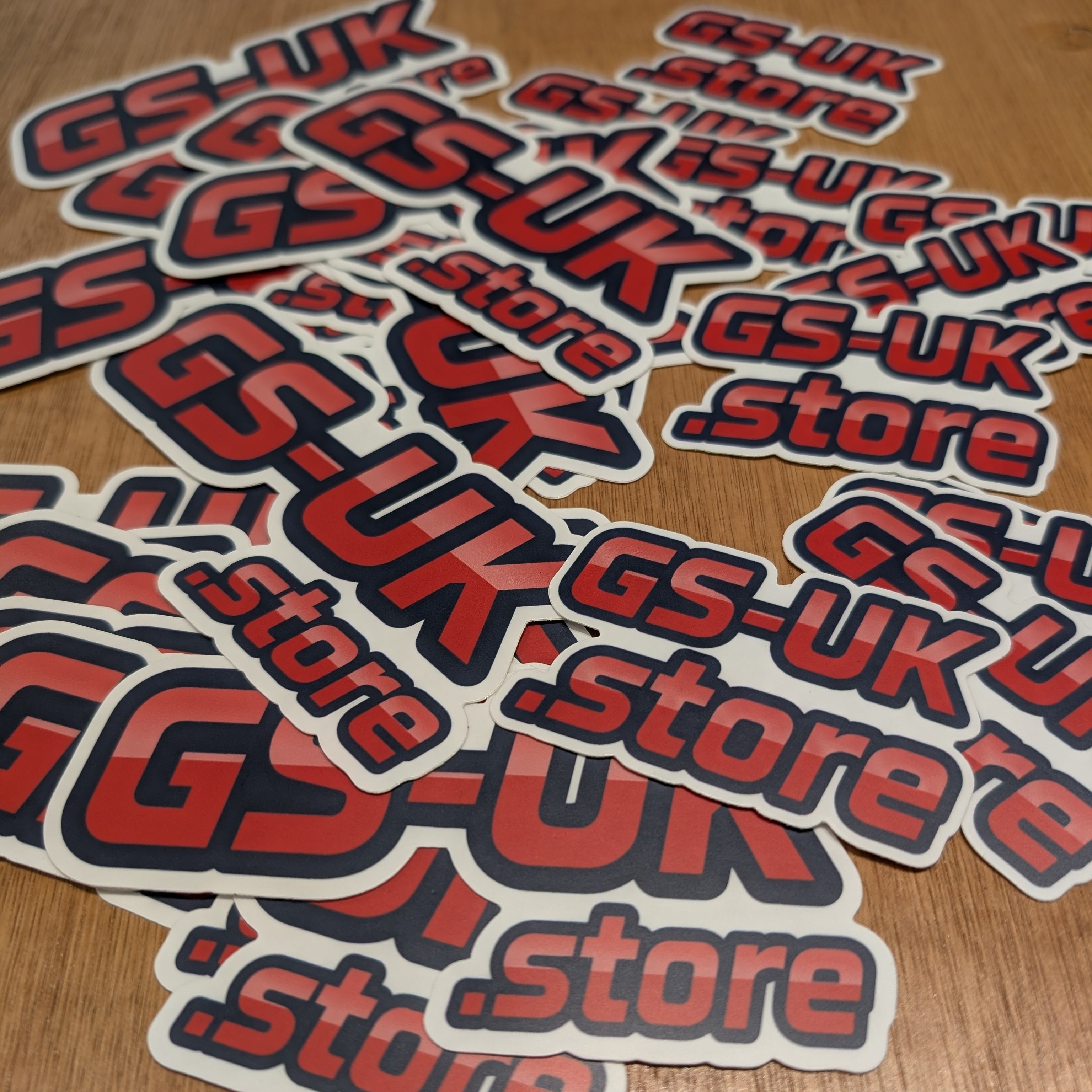 Stack of GS-UK store stickers on a wooden surface